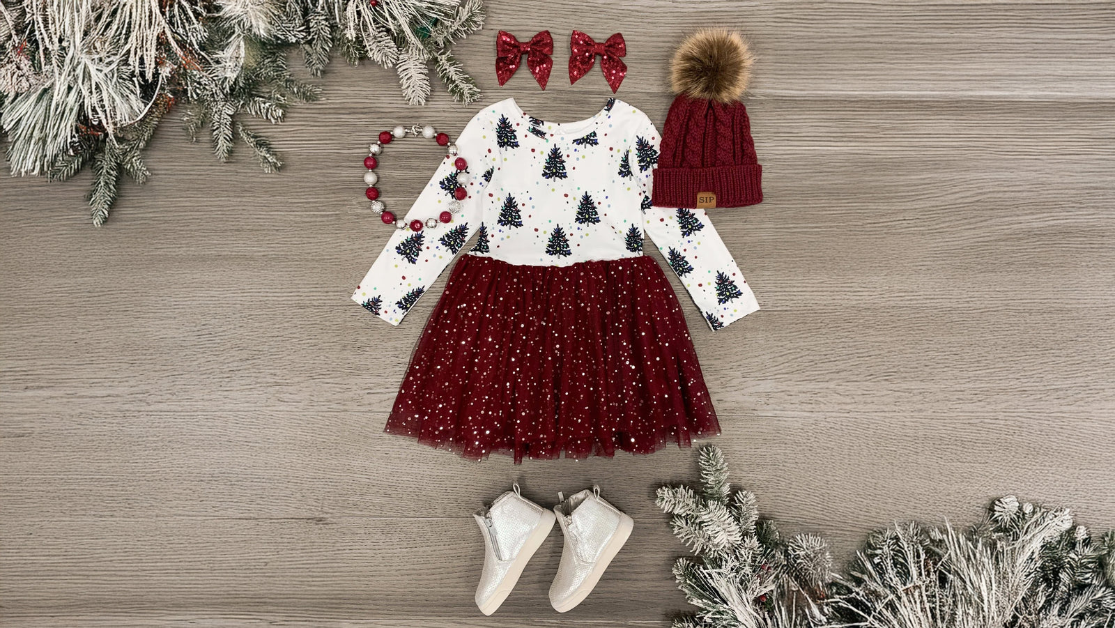 Girls' holiday dress featuring a white bodice with an allover winter tree print, long sleeves, and a burgundy tulle tutu skirt with silver sparkles. Made from ultra-soft, cozy fabric, this Burgundy Christmas Tree Tutu Dress is perfect for holiday festivities, combining comfort and feminine flair.